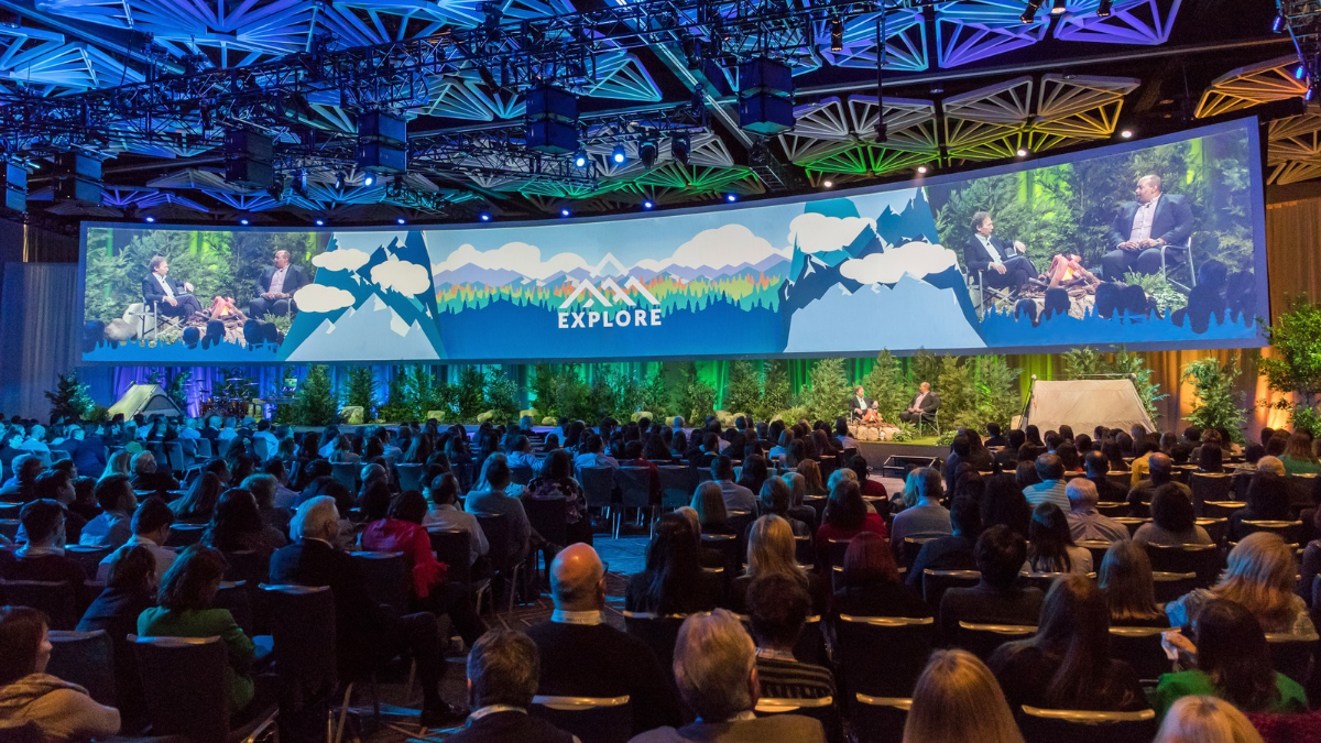 Live stage with a speaker in a large room filled with people
