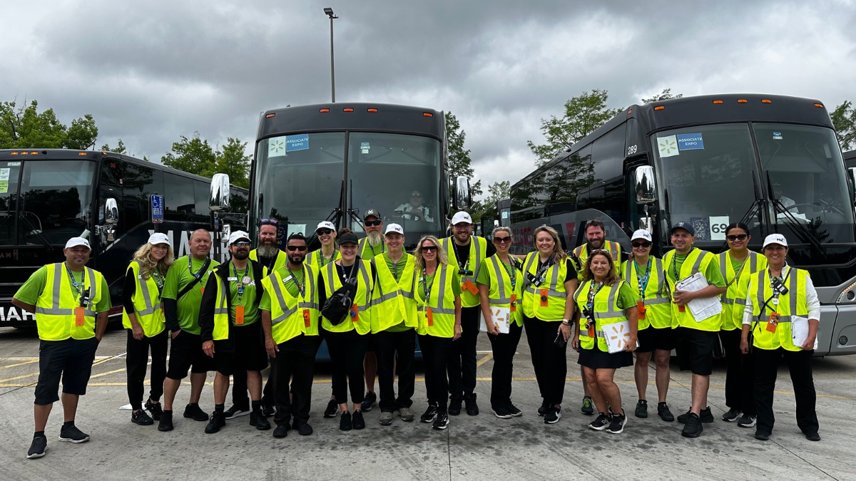 transportation team wearing vests in front of busses
