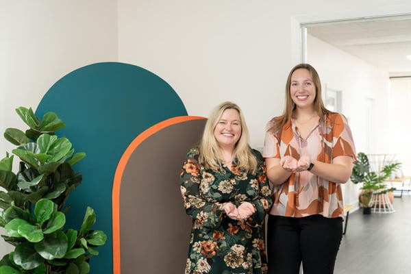 Two women smiling with open hands, representing connection and Give to gain.