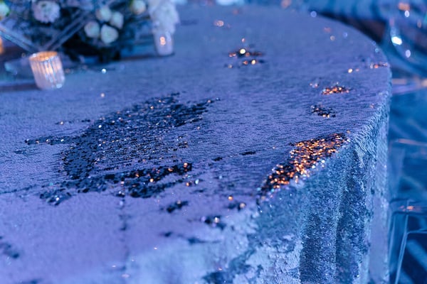 Close-up of a shimmering, sequined tablecloth with candlelight reflections