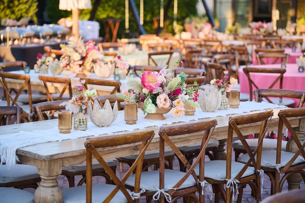 Long banquet table with wooden chairs, floral centerpieces, and elegant table settings.