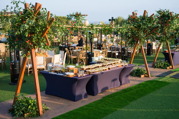Outdoor bar or service station surrounded by greenery and wooden structures in a garden venue.