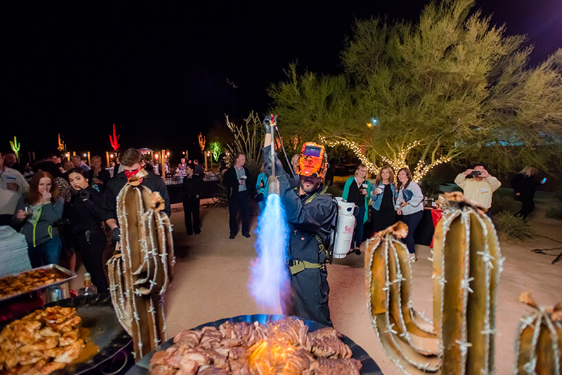 man cooking meat with fire thrower