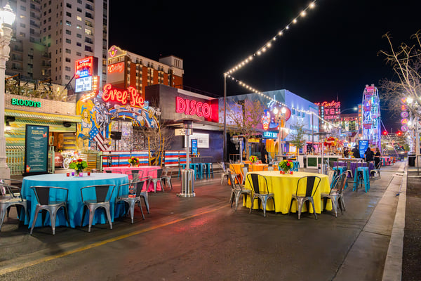 Street event with colorful tables and string lights. 