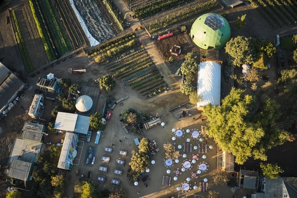 Aerial view of farmland with event seating and structures set among crops.