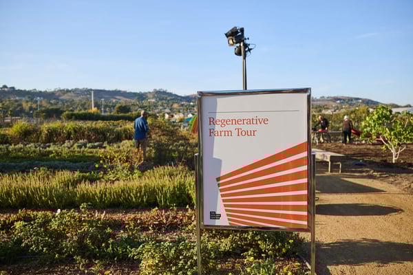 Event signage displayed at the entrance of an outdoor venue in a vineyard.