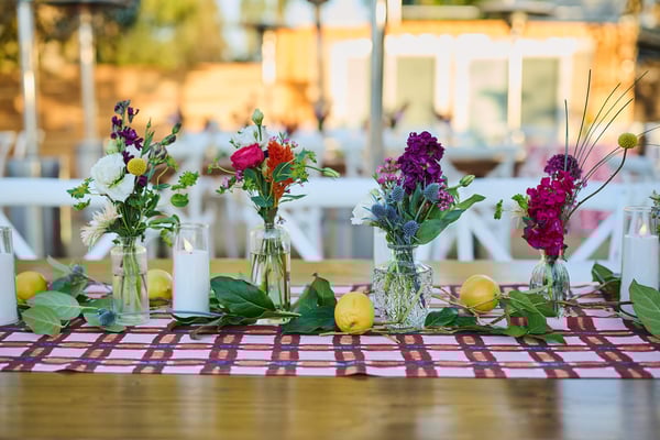 Long dining table decorated with colorful flowers and a patterned runner.