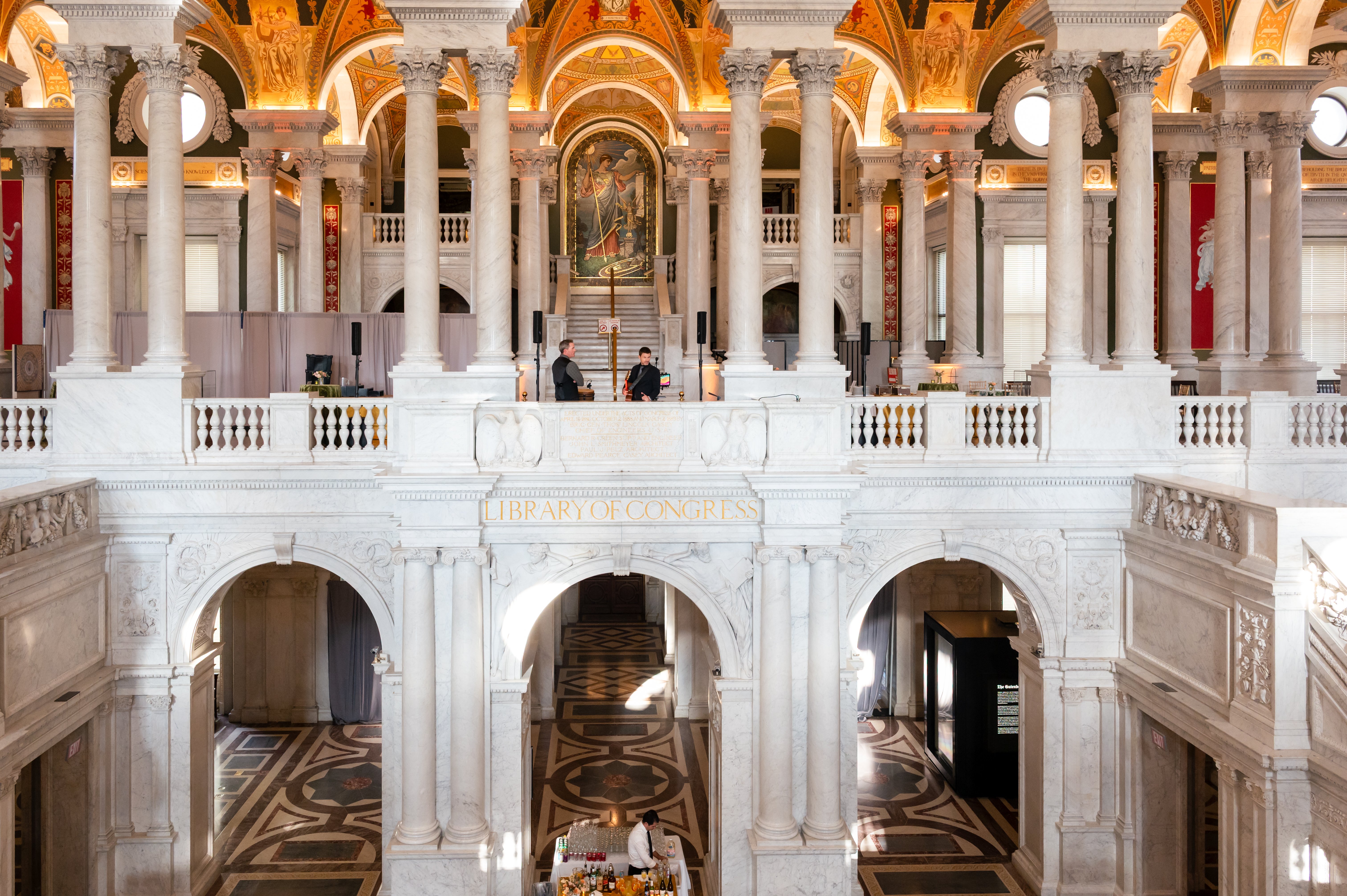 Grand interior of the Library of Congress with ornate columns, arches, and a central balcony.