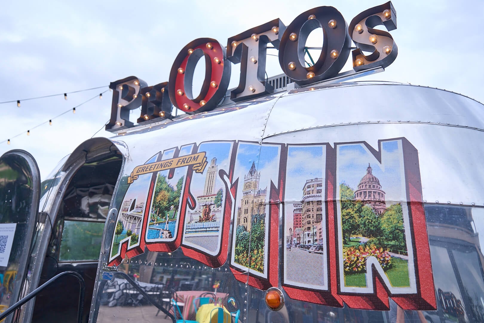 Vintage trailer with illuminated PHOTOS sign and colorful Austin-themed graphics.