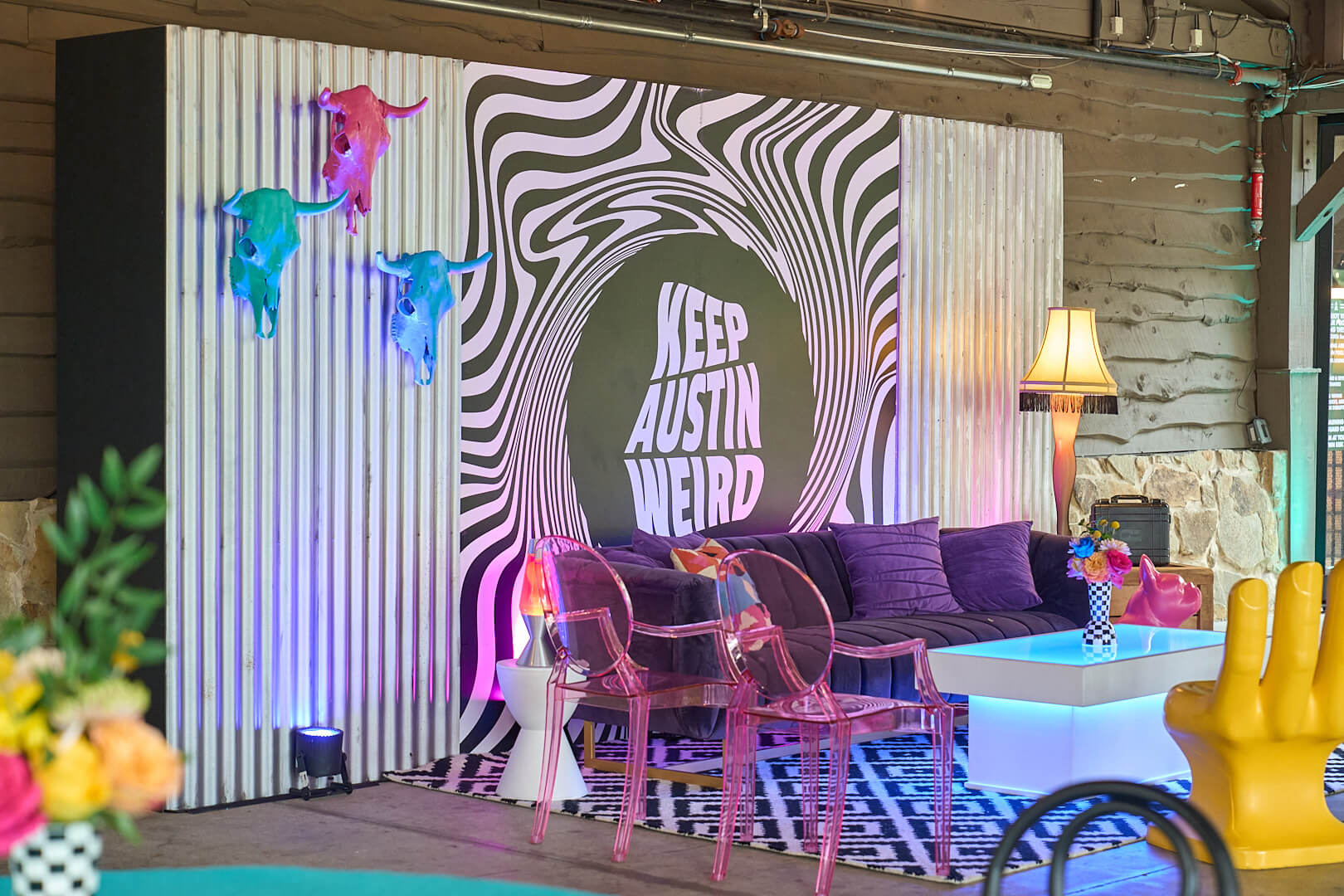 Lounge area with colorful lighting and a Keep Austin Weird mural in a modern event setting.