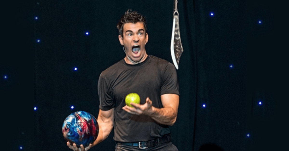 Entertainer juggles an apple, bowling ball, and knife.