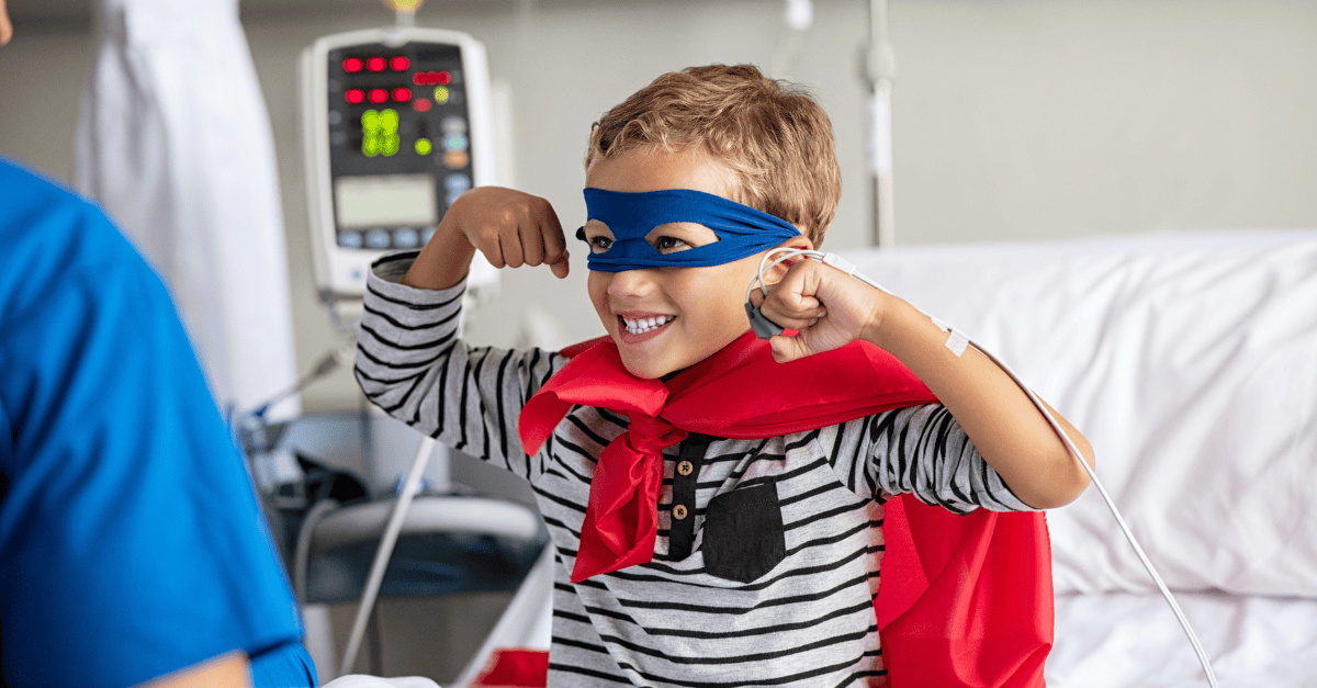 Child dressed as a superhero in a hospital bed.
