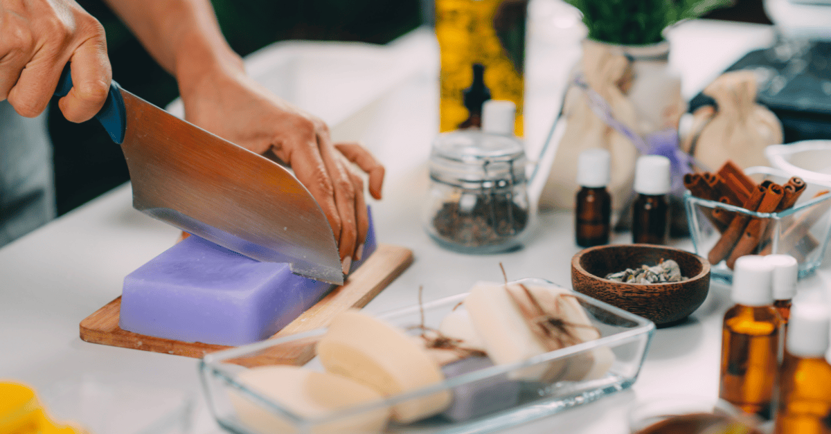 Handmade soap being cut beside essential oils.
