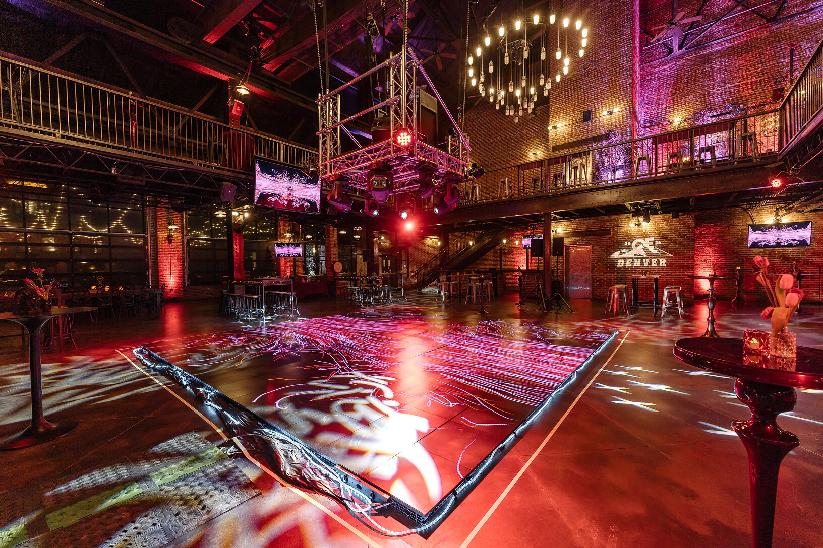 Industrial event venue with dramatic red lighting and projected floor graphics.
