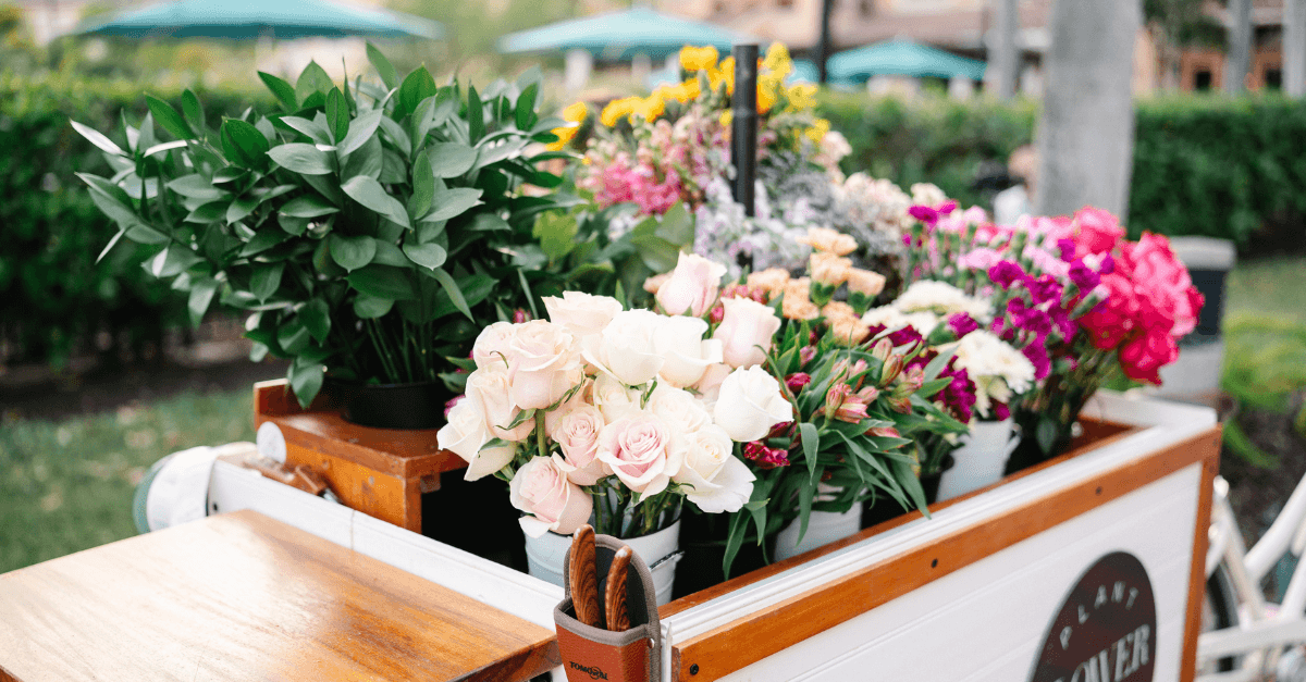 Mobile flower cart filled with fresh plants and colorful blooms in an outdoor setting.
