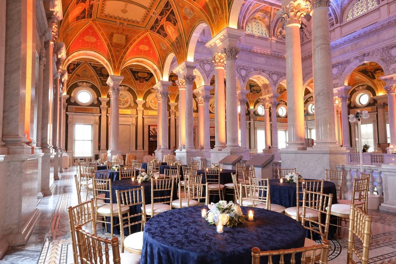 Elegant dining setup inside a historic hall with vaulted ceilings, arches, and gold chairs.