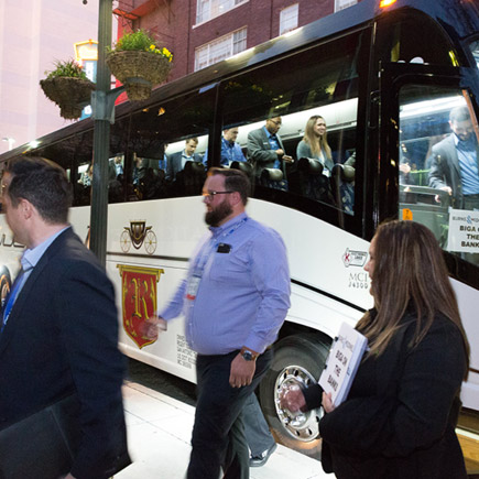 A group of event attendees exiting a parked coach bus